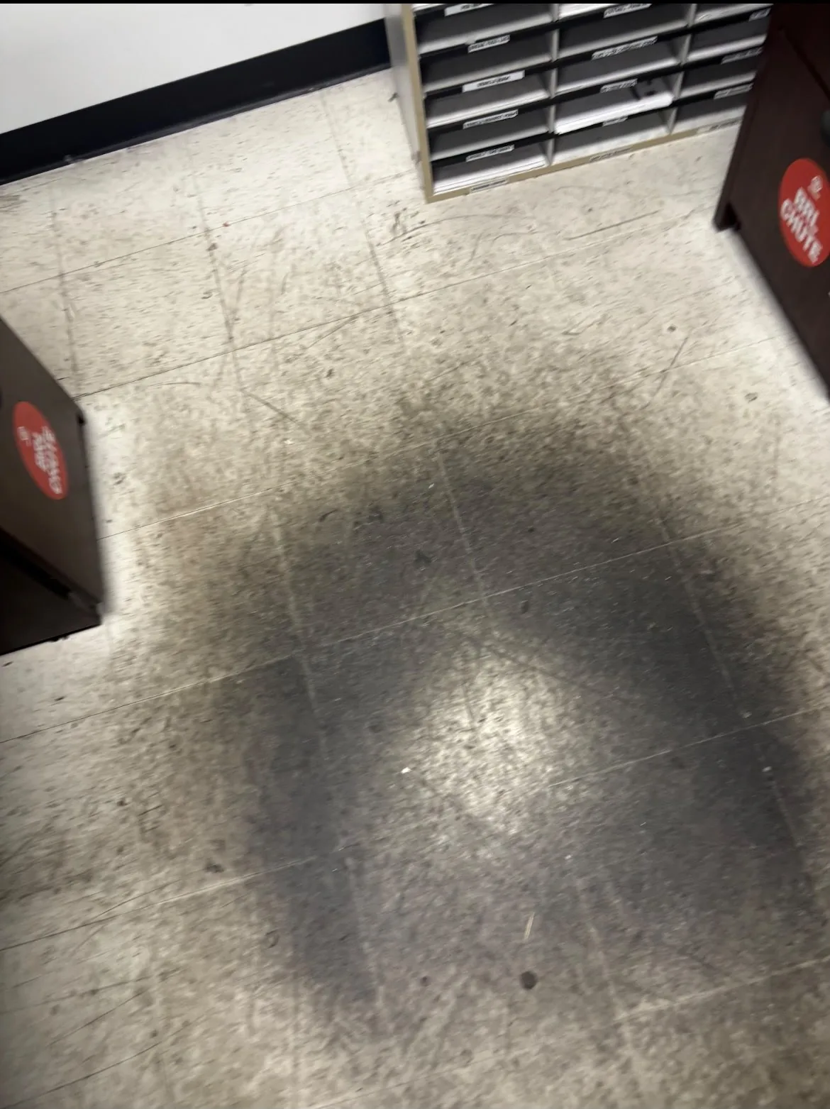 Mailroom tile floor before cleaning, dark scuff marks