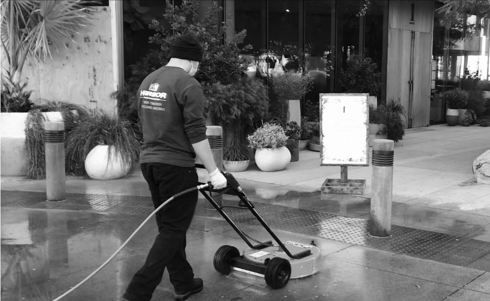 Harbor crew power washing a commercial walkway with a surface cleaner